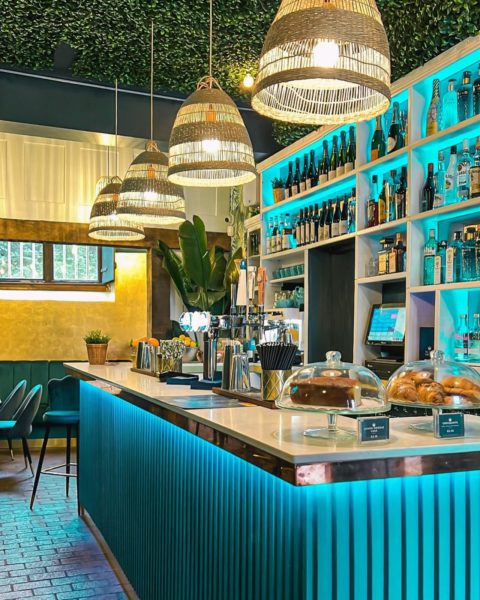 Interior of the Ocean Club, showing the bar area with a blue and gold colour scheme, Both the bar itself and the shelves behind are illuminated in a blue light. The venue has a very contemporary feel.